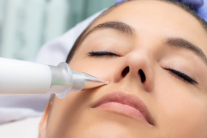 Woman With a Plasma Pen Touching Her Face